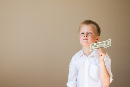 Happy smiling child with money (20 dollars) in hand on grey backgroundの写真素材