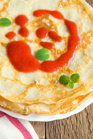 Pancakes with strawberry sauce and mint over rustic wooden backgroundの写真素材