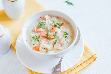 Salmon soup with noodles and vegetables over wooden table with copy spaceの写真素材