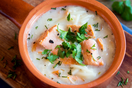 Salmon soup with noodles and vegetables in ceramic bowl close upの写真素材