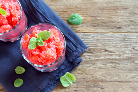 Strawberry granita with mint (frozen dessert) in portion glasses on rustic wooden background with copy spaceの写真素材