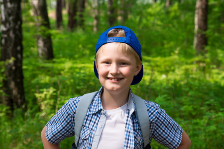 Young boy (child, teen) hiking and having fun in summer forest, closeup portrait in sun light with copy spaceの写真素材