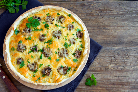 Homemade french quiche pie with mushrooms (champignons) and cheese over rustic wooden backgroundの写真素材