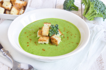 Homemade spicy broccoli cream soup with croutons in white bowl - healthy green vegetarian foodの写真素材