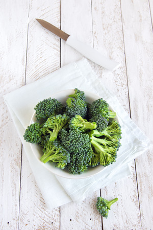 Healthy green organic raw uncooked broccoli on white wooden table with copy spaceの写真素材