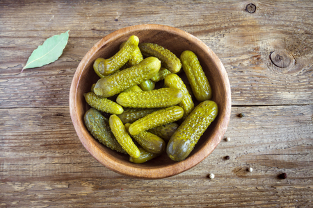 Pickles. Bowl of pickled gherkins (cucumbers) over rustic wooden background with copy space.の写真素材