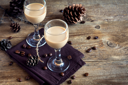 Irish cream coffee liqueur with coffee beans, Christmas decoration and cones over rustic wooden background - homemade festive Christmas alcoholic drinkの写真素材
