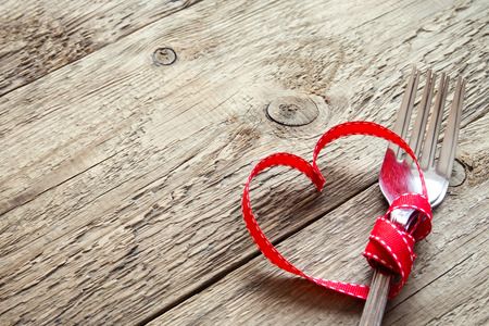 Table setting (two forks) for Valentine's Day with red hearts on rustic wooden background with copy space. Love, romance, love to eat or Valentine's day concept.の写真素材