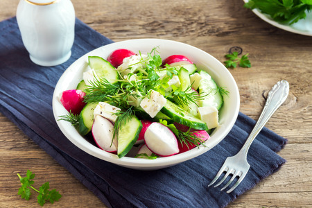 Spring salad with fresh cucumber, radishes, feta cheese, herbs, sprouts in bowl on wooden background - healthy detox diet vegan vegetarian salad mealの写真素材