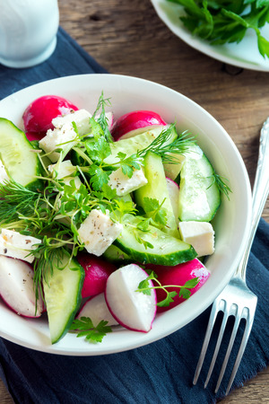 Spring salad with fresh cucumber, radishes, feta cheese, herbs, sprouts in bowl on wooden background - healthy detox diet vegan vegetarian salad mealの写真素材