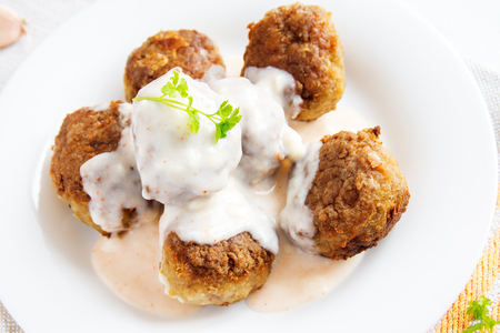 Meatballs with white creamy sauce and mash on white plate close upの写真素材