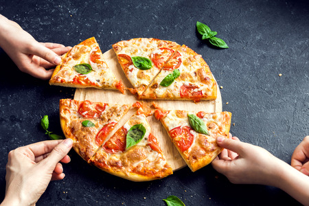 People Hands Taking Slices Of Pizza Margherita. Pizza Margarita and  Hands close up over black background.の写真素材