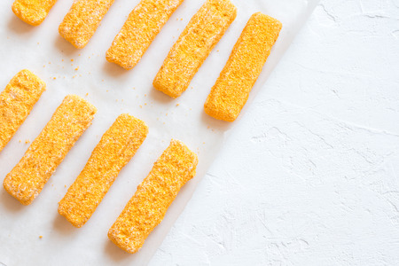 Frozen fish sticks, fish fingers on paper and white background, copy space. Convenience food, seafood, fish food sticks fingers.の写真素材