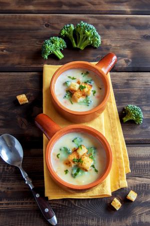 Vegetable and cheddar cheese cream soup with broccoli and croutons over wooden background with copy space - homemade healthy organic vegetarian vegan diet fresh food meal dish soup lunchの写真素材