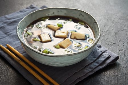 Japanese miso soup in ceramic bowl on black stone table, copy space. Asian miso soup with tofu.の写真素材