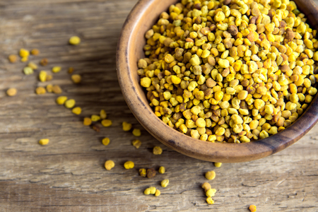 Bee pollen in bowl over wooden background. Healthy organic raw diet vegetarian food ingredient - bee pollen.の写真素材