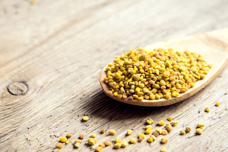 Bee pollen in spoon over wooden background. Healthy organic raw diet vegetarian food ingredient - bee pollen.の写真素材