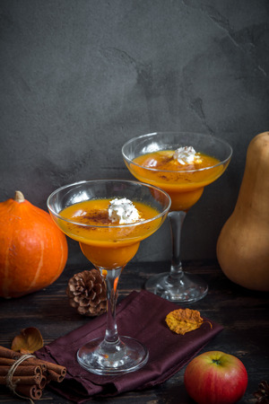 Fall Seasonal Drinks. Thanksgiving and Halloween Cocktails. Margarita Cocktail with Pumpkin Pie Spices and Whipped Cream on wooden table with autumn decor.の写真素材
