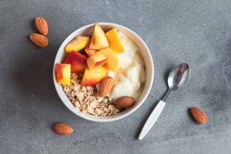 Homemade oatmeal granola with yogurt and peaches in bowl for healthy breakfast. Cereal and fruit breakfast bowl with yogurt.の写真素材