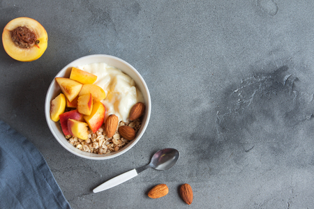 Homemade oatmeal granola with yogurt and peaches in bowl for healthy breakfast. Cereal and fruit breakfast bowl with yogurt.の写真素材