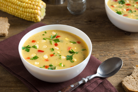 Homemade Corn Chowder Soup in white bowl. Vegetarian creamy corn soup with greens and vegetables.の写真素材