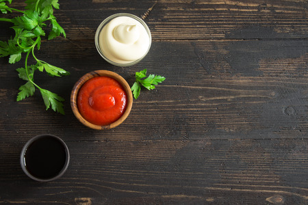 Ketchup, mayonnaise and soy sauce - assorted sauces on on dark wooden background, copy spaceの写真素材