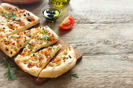 Traditional Italian Focaccia with tomatoes, black olives and rosemary - homemade flat bread focacciaの写真素材
