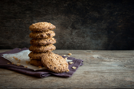Homemade oatmeal cookies with lin and sesame seeds on dark rustic wooden table, copy space. Healthy vegan oat cookies.の写真素材