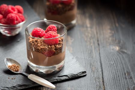 Chocolate dessert in glasses with raspberries. Chocolate mousse or pudding in portion glasses with fresh berries, copy space.の写真素材
