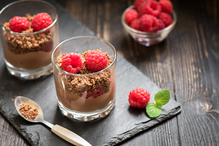 Chocolate dessert in glasses with raspberries. Chocolate mousse or pudding in portion glasses with fresh berries, close up.の写真素材