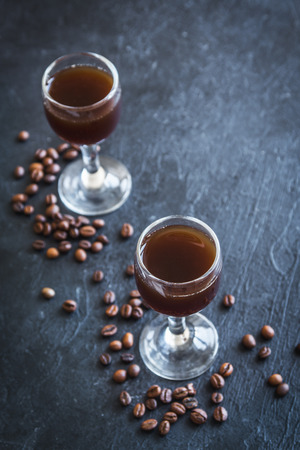 Coffee liqueur with coffee beans on rustic black stone background, copy space. Homemade coffee liqueur.の写真素材