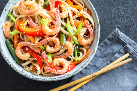 Stir fry with udon noodles, shrimps (prawns) and vegetables. Asian healthy food, meal, stir fry in bowl over black background, copy space.の写真素材