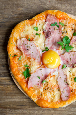 Pizza Carbonara on wooden background. Italian Pizza Carbonara with Bacon, Egg and Cheese top view, copy space.の写真素材