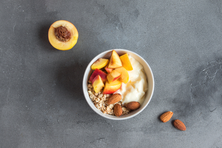 Homemade oatmeal granola with yogurt and peaches in bowl for healthy breakfast. Cereal granola and fruit breakfast bowl with yogurt.の写真素材