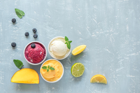 Three various fruit and berries ice creams on blue background, copy space. Frozen yogurt or ice...