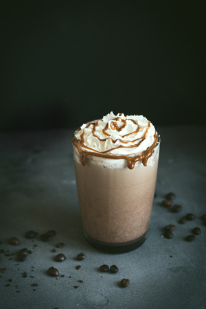 Cold Frappe Coffee (frappuccino) with whipped cream and caramel on dark background, copy space.の写真素材
