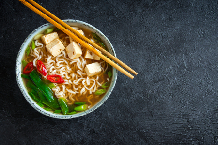 Japanese ramen soup with tofu on dark stone background. Miso soup with ramen noodles and tofu in ceramic bowl, asian traditional food.の写真素材