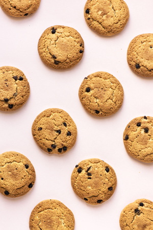 Chocolate chip cookies on pink pastel background, top view.