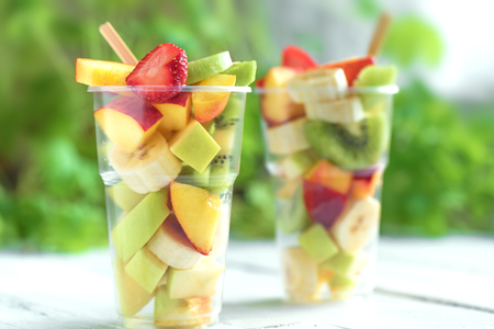 Fruit salad in plastic cups takeaway. Sliced organic fruits and berries, healthy snack to go, copy space.の写真素材