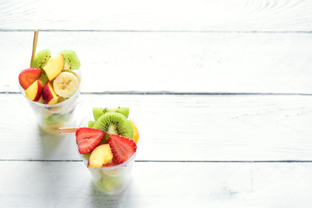 Fruit salad in plastic cups takeaway. Sliced organic fruits and berries, healthy snack to go, copy space.の写真素材