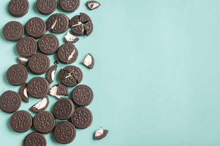 Chocolate and cream sandwich cookies on blue pastel background, top view, copy space.