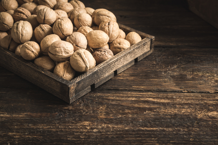 Organic Walnuts in rustic wooden box, top view, copy space. Seasonal harvest of walnuts.の写真素材