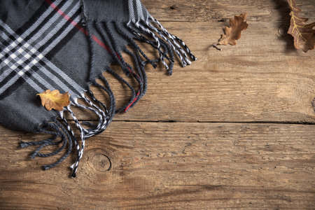 Autumn. Brown checkered plaid with dry oak leaves on wooden background.の写真素材