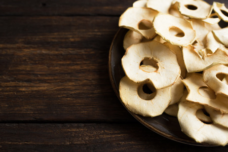 Apple fruit chips on dark wooden background, copy space, healthy vegan snack.の写真素材