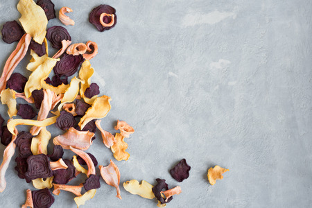 Various vegetable chips on grey background, copy space. Assorted dehydrated beetroot, carrot, pumpkin vegetable chips - healthy vegan snack.の写真素材
