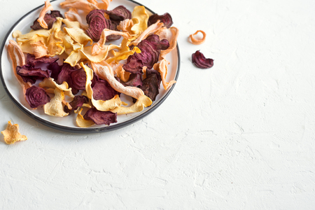Various vegetable chips on white background, copy space. Assorted dehydrated beetroot, carrot, pumpkin vegetable chips - healthy vegan snack.の写真素材