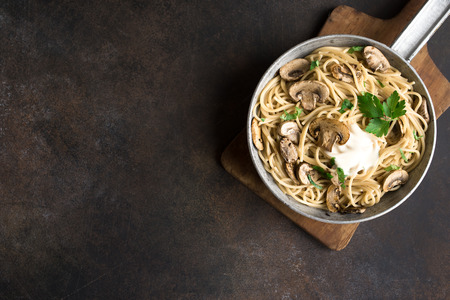 Mushroom Spaghetti Pasta and cream sauce on rustic background, top view, copy space. Homemade italian pasta with champignon mushroom in cooking pan.の写真素材