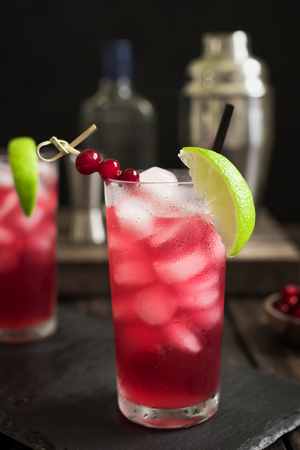 Cape Codder Cocktail with lime and ice. Cranberry and vodka alcohol Cape Codder Cocktail on dark wooden background.の写真素材