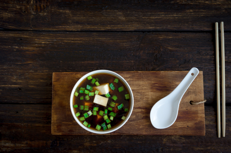 Japanese miso soup in ceramic bowl on dark wooden background, copy space. Asian miso soup with tofu.の写真素材