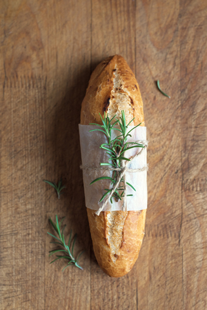 Fresh homemade bread with rosemary in rustic wooden box, top view. Sourdough mini baguette bread.の写真素材